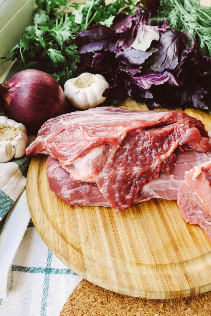 A rustic scene of raw pork and fresh vegetables on a wooden cutting board, ideal for cooking themes.