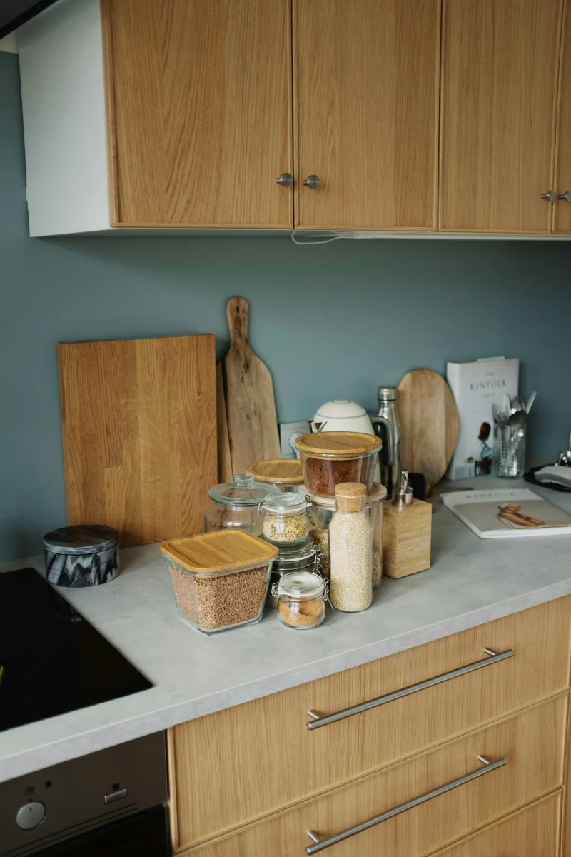 Modern kitchen countertop with cookbooks, containers, and wooden decor.