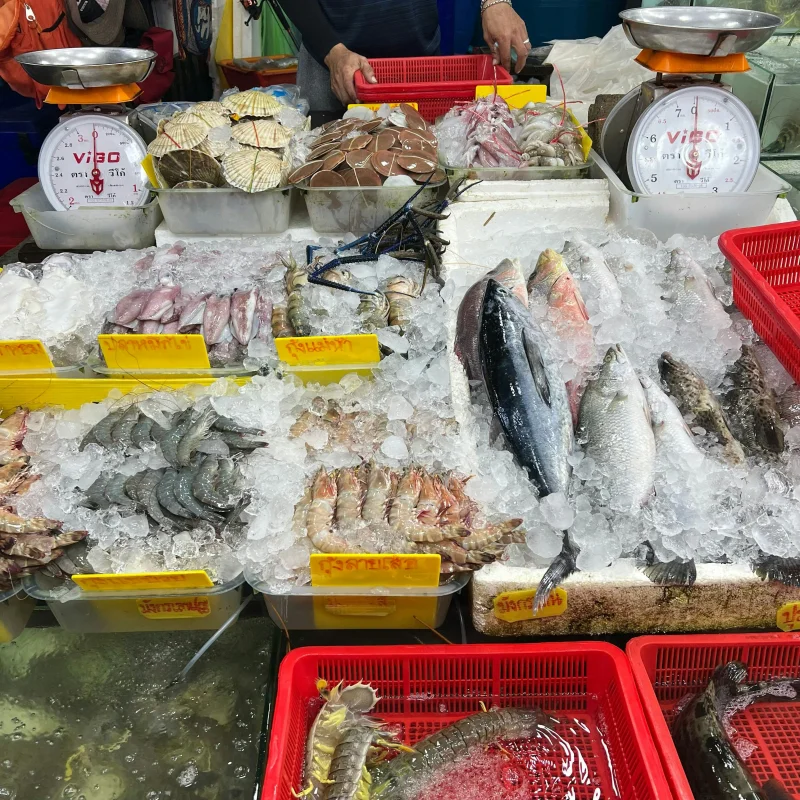 Vibrant seafood market stall in Phuket, Thailand showcasing fresh fish and shellfish on ice.