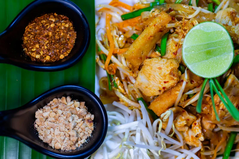 Delicious Pad Thai served with lime, peanuts, and chili flakes, embodying authentic Thai cuisine.