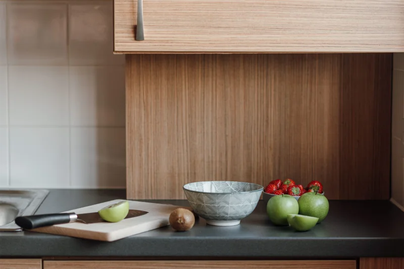 Fresh healthy green apples and kiwi with bowl of fresh strawberries placed on counter in kitchen near wooden cutting board and knife
