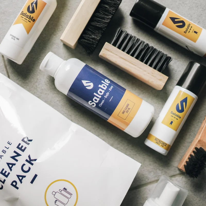 Top view of assorted shoe cleaning products and brushes on a surface.