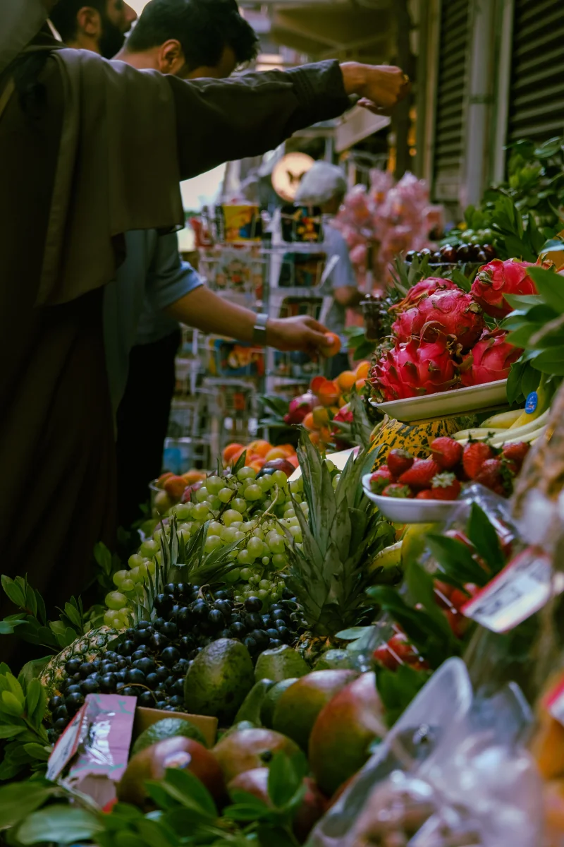 Bustling market scene featuring colorful fresh fruits and diverse shoppers, capturing dynamic market life.