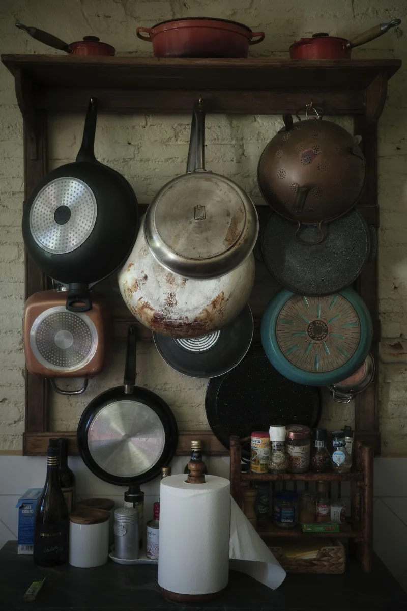 Cozy kitchen corner with a variety of hanging pans and spices, exuding rustic charm.
