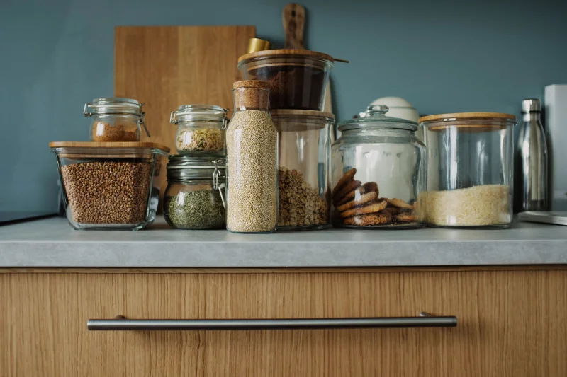 A stylish kitchen setup featuring various ingredients stored in clear glass jars on a wooden counter.