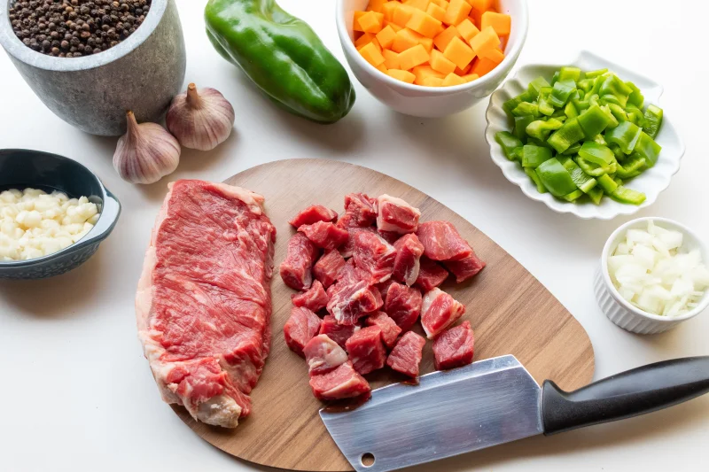A variety of fresh ingredients including beef, vegetables, and seasonings ready for a homemade stew.
