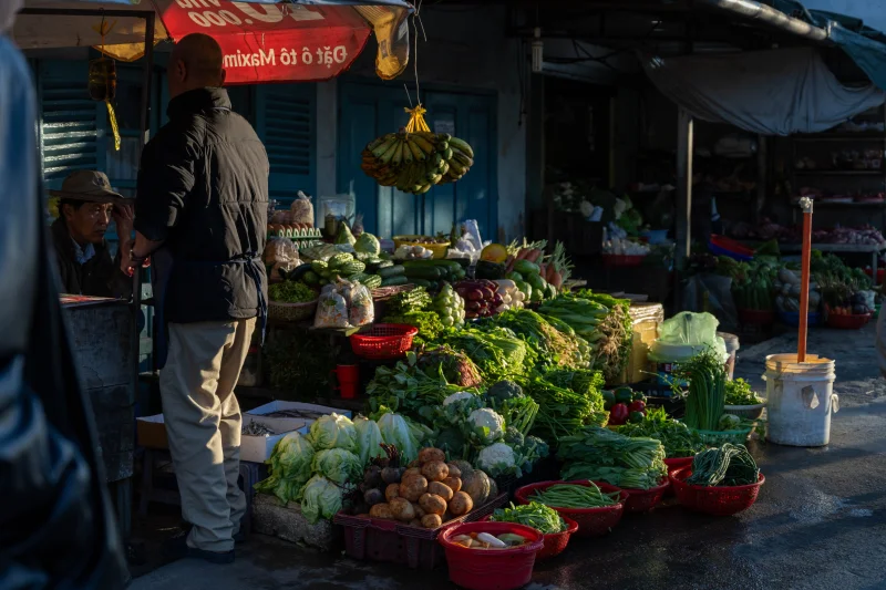 Street market in Dalat, Vietnam with fresh vegetables and early morning shoppers.
