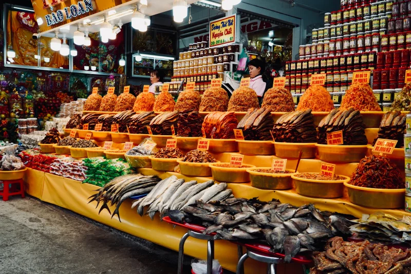 Colorful assortment of dried goods and fresh fish at a bustling Vietnamese market stall.