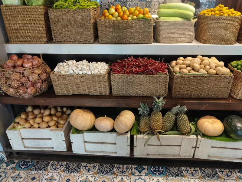 A vibrant market display featuring a variety of fresh vegetables and fruits in wicker baskets and wooden crates.