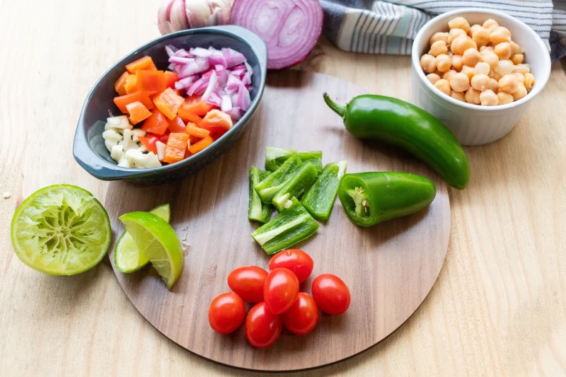 Colorful chopped ingredients including tomatoes, peppers, and lime for a homemade salsa.