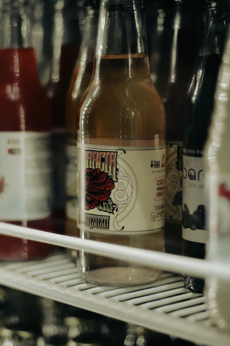 Close-up of various bottled drinks on a fridge shelf with focus on labels.