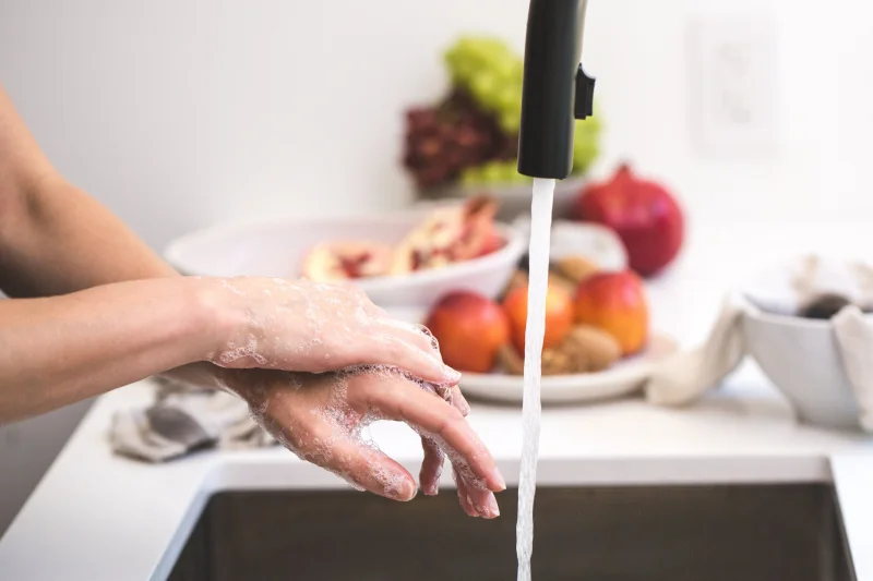 Hands washing with soap under faucet, emphasizing cleanliness and hygiene.