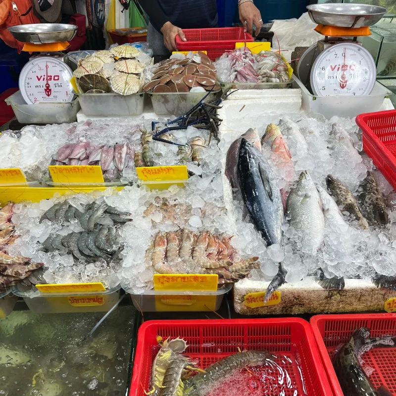Vibrant seafood market stall in Phuket, Thailand showcasing fresh fish and shellfish on ice.