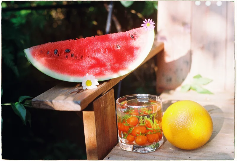 A vibrant summer display of watermelon, orange, and floral glass outdoors.