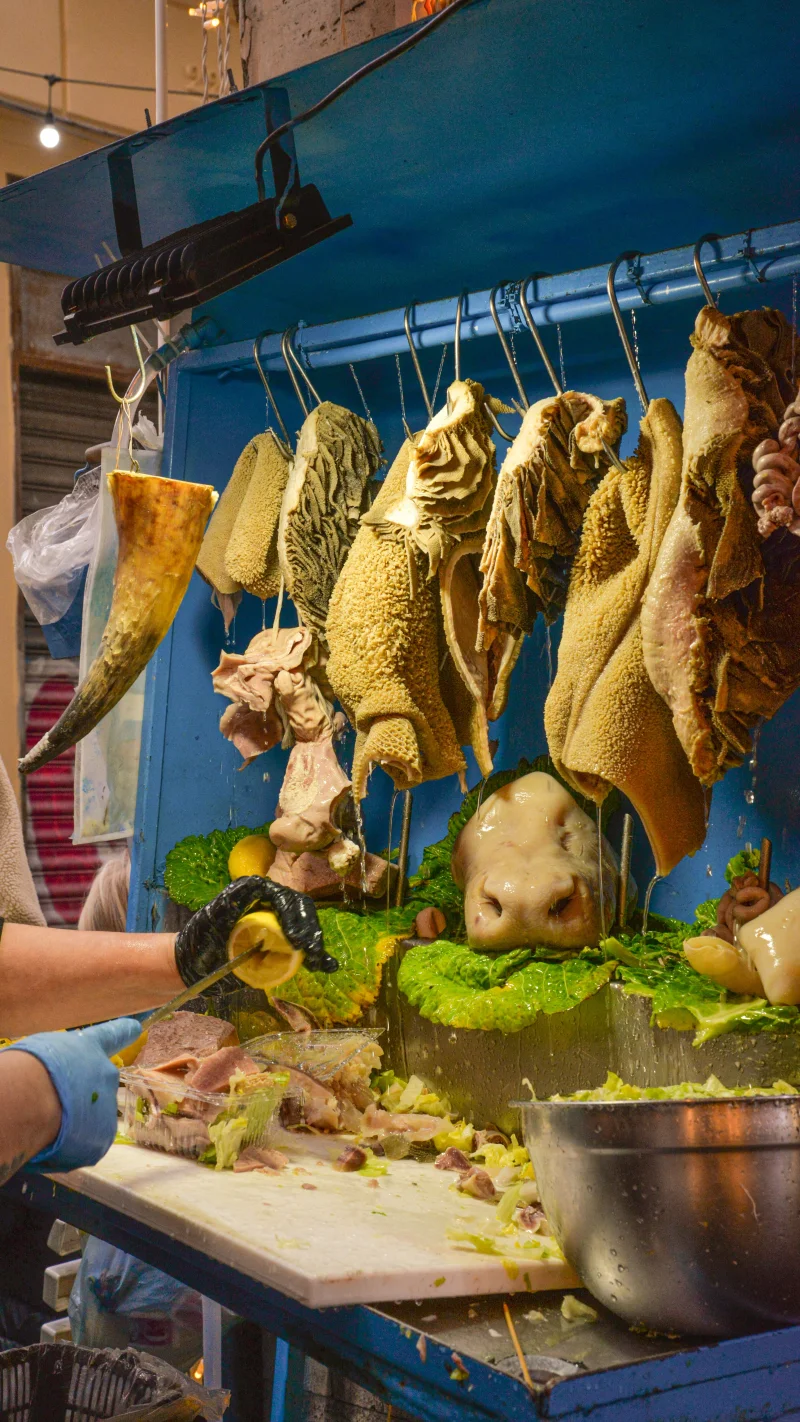 A vibrant display of various meats hanging in an outdoor market stall, showcasing traditional selection.