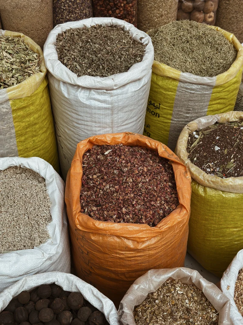 An array of colorful spices in sacks at a traditional market, showcasing diverse textures and colors.