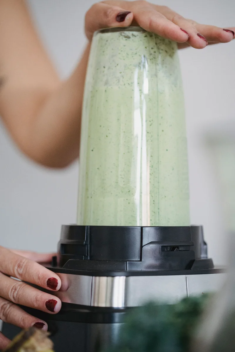 A close-up of hands blending a nutritious green smoothie, perfect for a healthy lifestyle.