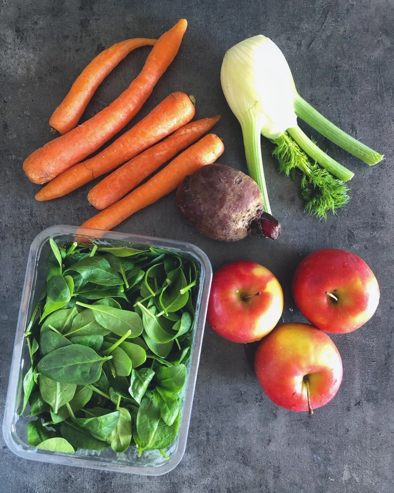 Colorful arrangement of fresh fruits and vegetables on dark background.