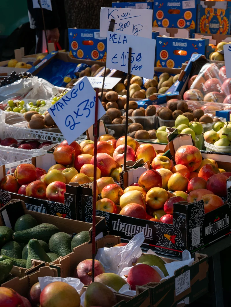 Colorful variety of fruits displayed at an outdoor market with price tags.