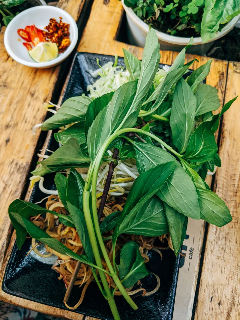 A vibrant display of fresh Vietnamese pho ingredients on a wooden table.