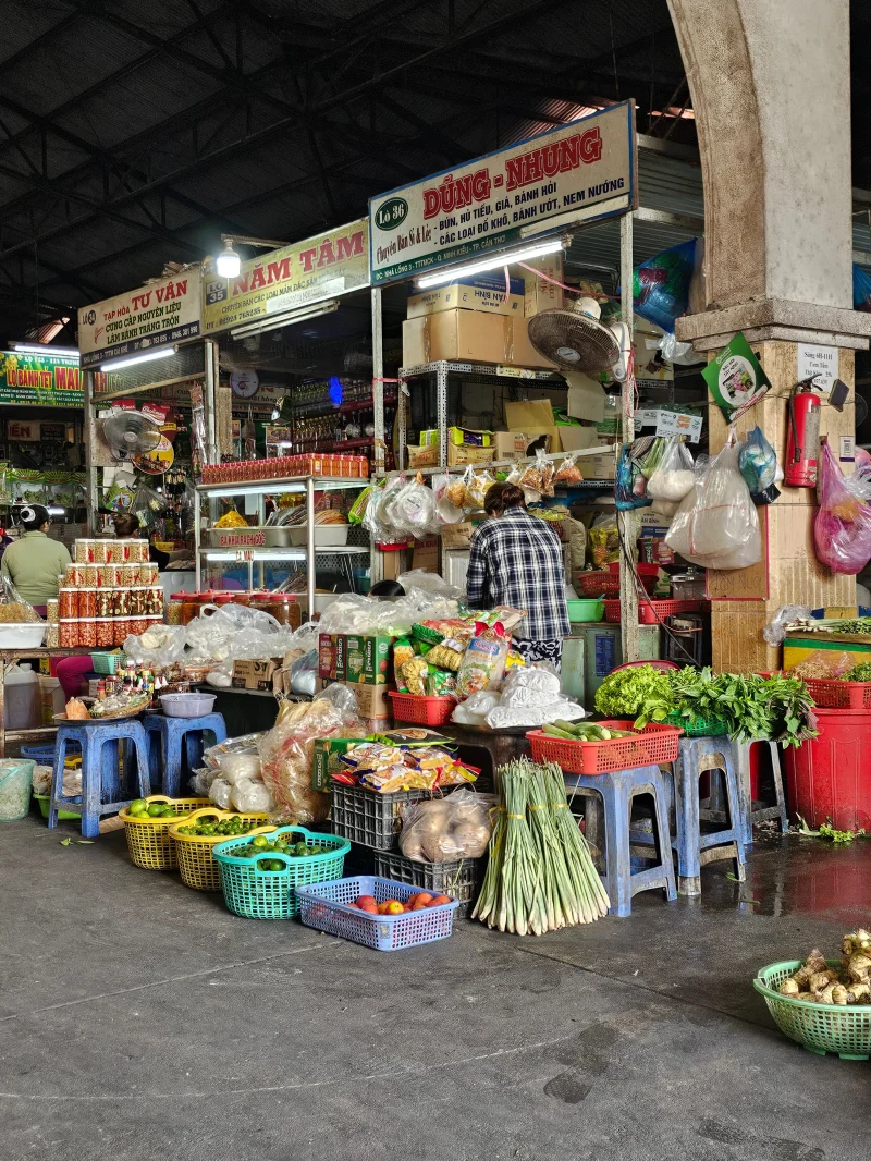 Colorful market stall in Vietnam showcasing fresh produce and local foods in a lively indoor setting.