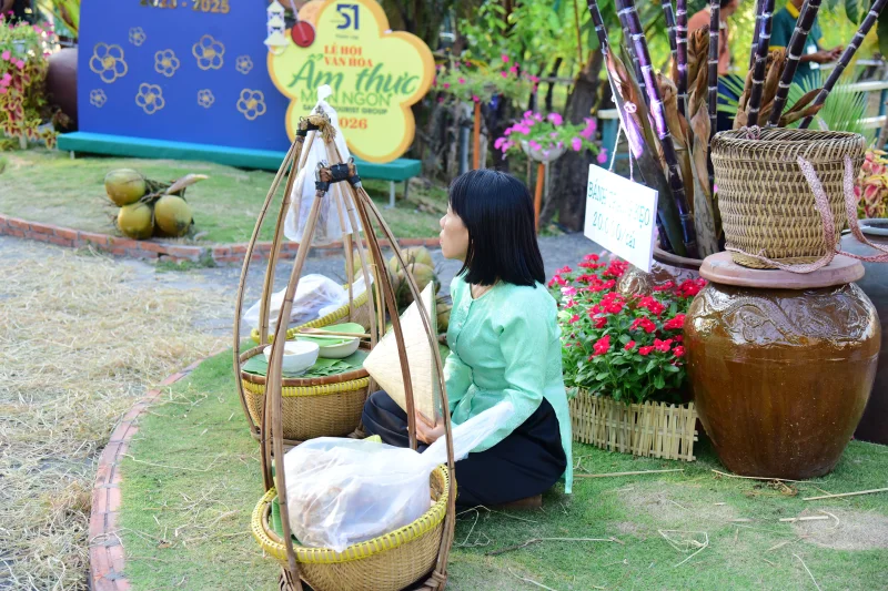 Woman in traditional attire selling goods at a Vietnamese market festival.