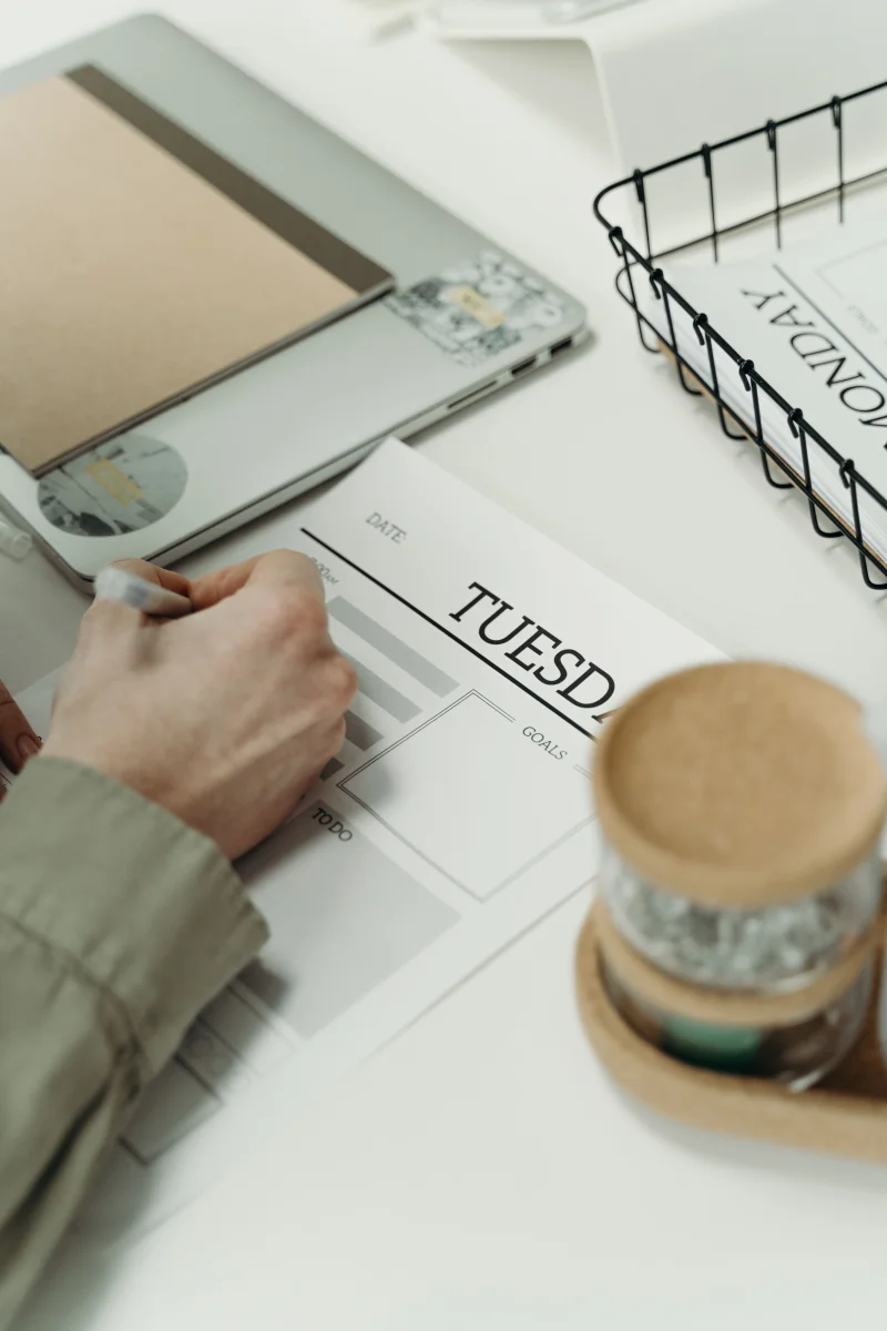 Person writing in a planner to organize weekly tasks and schedule.