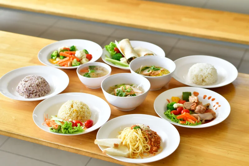 A variety of Asian and Italian dishes presented beautifully on a wooden table, showcasing diverse flavors.