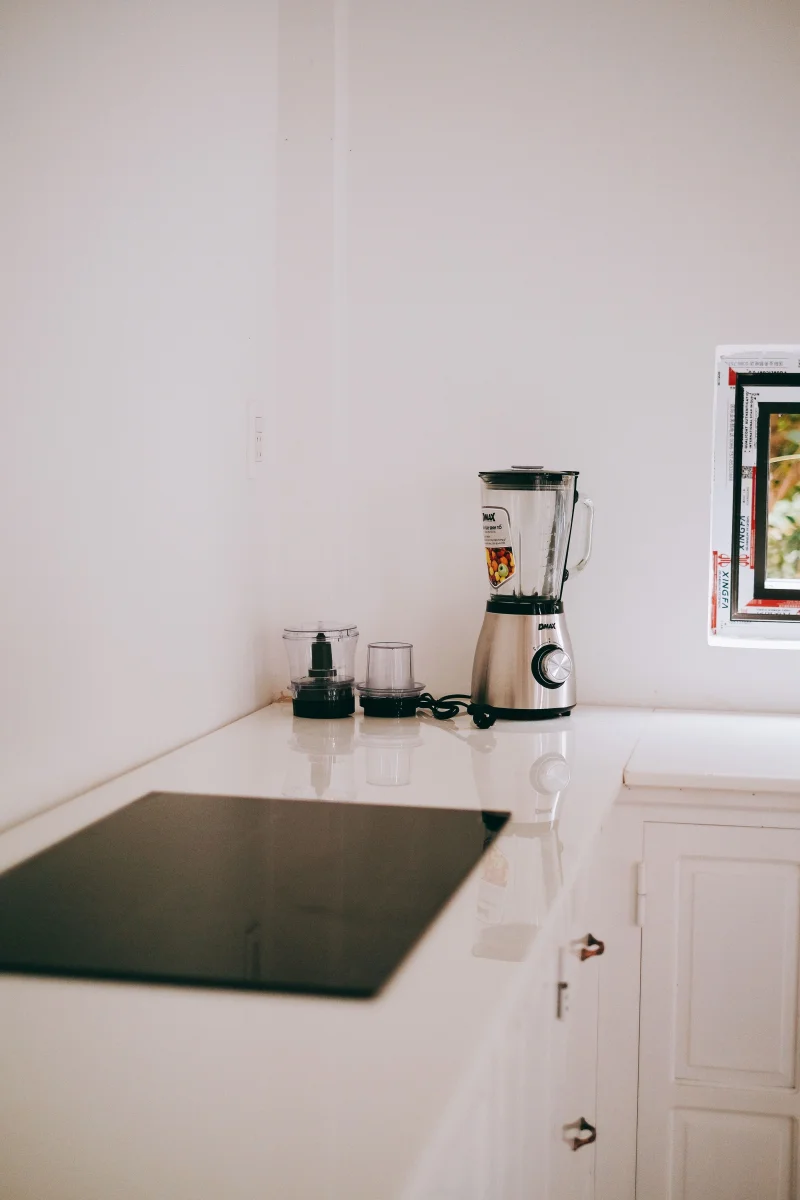 Stylish kitchen corner featuring a sleek blender and induction stove on a white countertop.