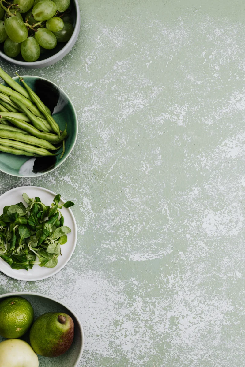 Top view of green vegetables and fruits in bowls, perfect for food blogs or healthy lifestyle marketing.