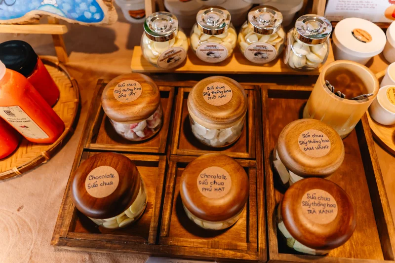 A close-up of assorted jars filled with different yogurt varieties, labeled and organized on a wooden tray.