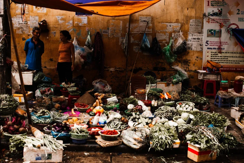 A vibrant outdoor market stall showcasing a variety of colorful fresh vegetables in a rustic street setting.