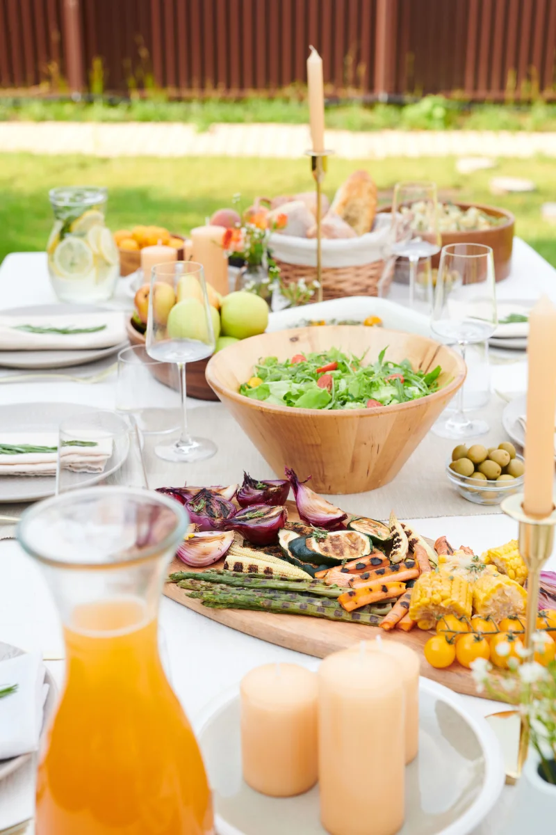 A beautiful outdoor dining setup featuring fresh salads, grilled vegetables, and vibrant fruits.