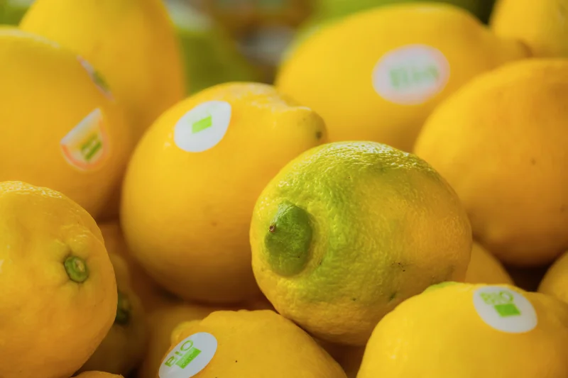 A close-up of fresh organic lemons adorned with bio stickers in vibrant yellow hues.
