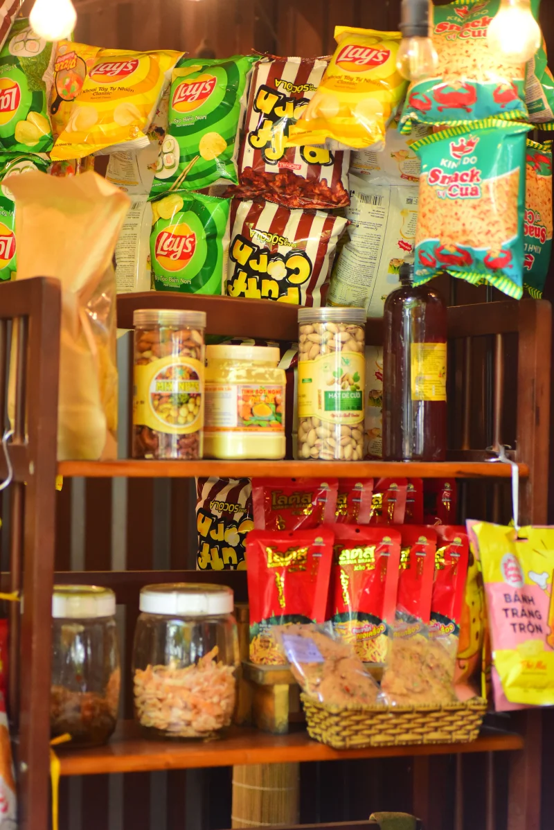 Colorful display of snack bags and bottles on a wooden shop shelf.